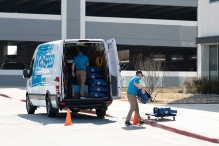 Two people taking equipment out of a van