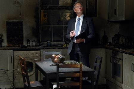 man with a tie standing in a burnt kitchen