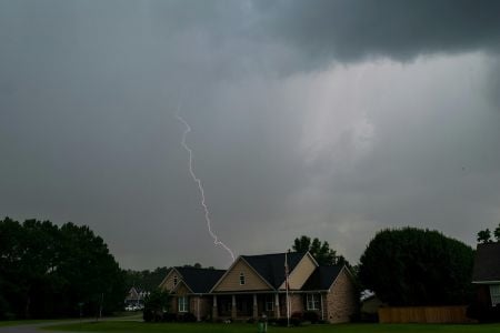 lightning bolt behind a home with a dark sky